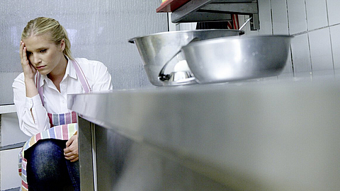 Fleischereifachverkäuferin sitzt gestresst auf dem Boden