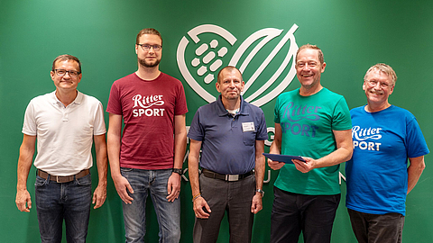 Rittersport-Team und BGN-Verantwortliche lächeln mit den Kooperationsdokumenten in den Händen | © BGN Rittersport-Team und BGN-Verantwortliche lächeln mit den Kooperationsdokumenten in den Händen