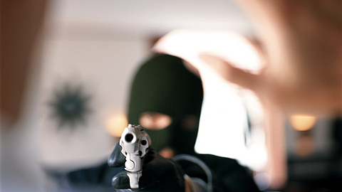 Ein Mann wird von einem Maskierten mit einer Waffe bedroht