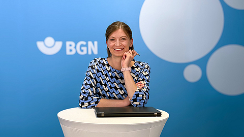 Lisa Fehrentz steht an einem runden Stehtisch, lächelt und hat einen Laptop vor sich auf dem Tisch stehen