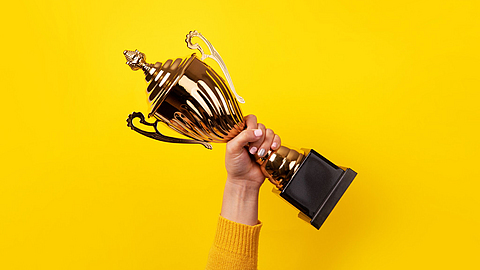 Hand mit Pokal | © alesmunt - stock.adobe.com Hand mit Pokal