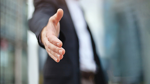 Geschäftsmann bietet Hand für Händedruck und Zusammenarbeit an