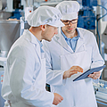 Zwei junge männliche Sicherheitsbeauftragte  kontrollieren die automatisierte Produktion in der Nahrungsmittelindustrie