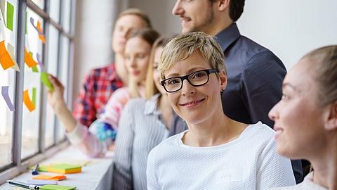 Lächelnde Frau arbeitet im Team in einem Workshop