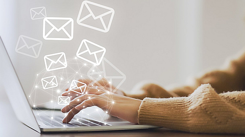 Frau nutzt Laptop und versendet Online-Nachrichten mit E-Mail-Symbol