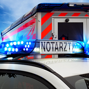 Teilansicht Feuerwehreinsatzfahrzeug mit Blaulicht und Notarztfahrzeug