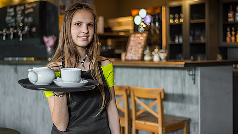 Porträt einer jungen Kellnerin, die im Café steht | © pavel siamionov - stock.adobe.com Porträt einer jungen Kellnerin, die im Café steht