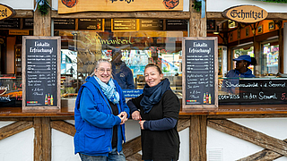 Ramona Pölzl-Rosenhammer (links), Chefin der Wurstbraterei Pölzl und ihre rechte Hand Jessica Stadler freuen sich über den Besuch der beiden BGN-Aufsichtspersonen. | © Martin Hangen München Die BGN auf dem Oktoberfest 2025