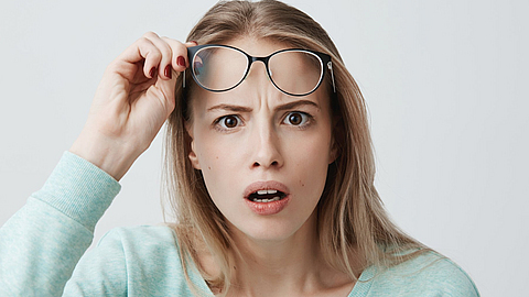 Eine Frau schaut sehr erstaunt und schiebt ihre Brille nach oben, um besser sehen zu können.