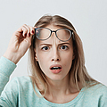 Eine Frau schaut sehr erstaunt und schiebt ihre Brille nach oben, um besser sehen zu können.