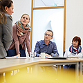 Fünf Personen sitzen am Tisch und besprechen das betriebliche Gesundheitsmanagement.