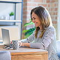 Glückliche Frau arbeitet am Laptop von zu Hause