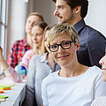 Lächelnde Frau arbeitet im Team in einem Workshop