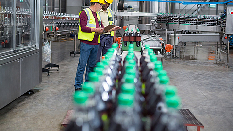 Zwei Mitarbeiter der Getränkeherstellung überwachen die Anlage