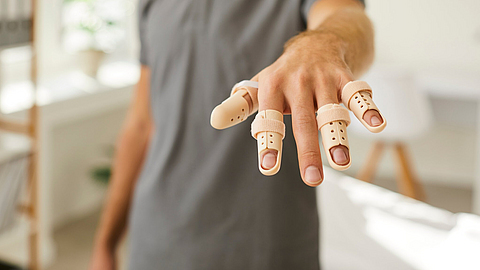 Mann mit Fingerverletzung trägt eine verstellbare Fingerschiene