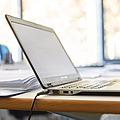 Ein Laptop steht auf einem Tisch, im Hintergrund eine Tasse.