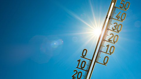 Rekordhitze, Thermometer mit strahlender Sonne und blauem Himmel im Hintergrund