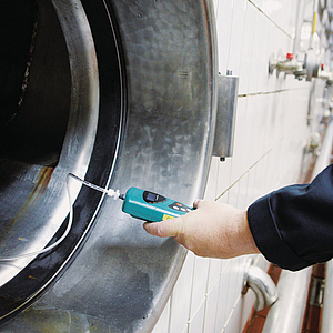 Brauereimitarbeiter misst einen Tank frei