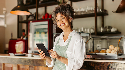 Unternehmerin mit einem digitalen Tablet in ihrem Café