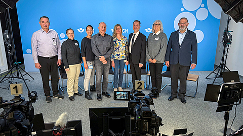 Zu sehen ist das Team der BGN-Arbeitsschutztagung 2024, die in einer Reihe nebeneinander in einem Filmstudio stehen.