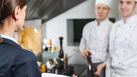 Einweisung des Restaurantleiters an sein Küchenpersonal in der Großküche