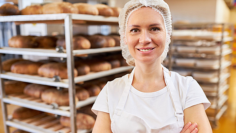 Junge Frau als Bäcker Lehrling mit verschränkten Armen