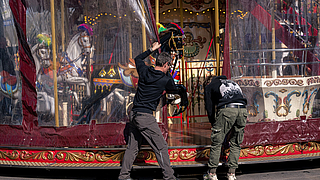 Schaustellergehilfen verschließen Venetian Carousel mit Plane