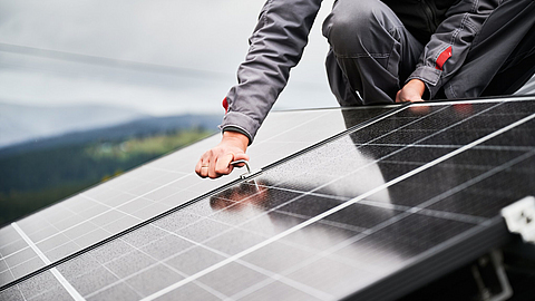 Techniker montiert Photovoltaik-Solarmodule auf dem Dach eines Hauses
