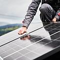 Techniker montiert Photovoltaik-Solarmodule auf dem Dach eines Hauses