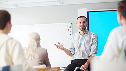 Ein Berufsschullehrer steht vor einer Klasse und erklärt etwas
