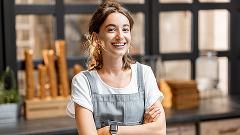 Junge Verkäuferin steht in einer Eisdiele an der Theke.