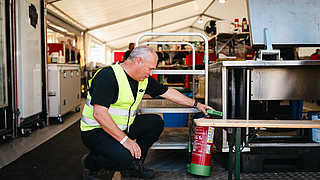 Kontrolle ist besser: BGN-Arbeitsschutzexperte Stephan Thomassohn überprüft einen Feuerlöscher im Cateringzelt des Highfield Festivals.