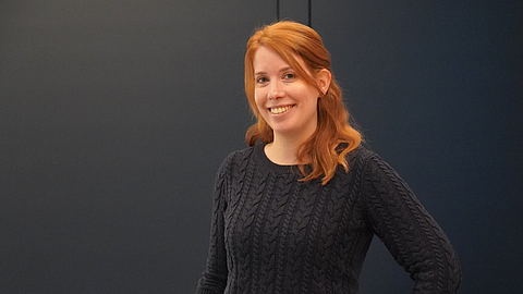 Maren Albrecht steht vor einem gelben Sessel. | © BGN | Ellen Weidenfeld Maren Albrecht steht vor einem gelben Sessel.