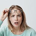 Eine Frau schaut sehr erstaunt und schiebt ihre Brille nach oben, um besser sehen zu können.