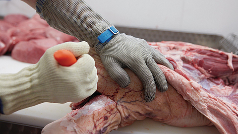 Ausbeinarbeit mit Schnittschutzhandschuh an Messer führender Hand und Stechschutzhandschuh an der anderen Hand | © Oliver Rüther / BGN Ausbeinarbeit mit Schnittschutzhandschuh an Messer führender Hand und Stechschutzhandschuh an der anderen Hand