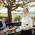 Positive Kellnerin demonstriert Besuchern das Open-Air-Restaurant