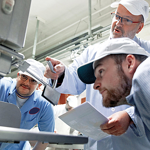 Fachkraft gibt zwei Kollegen eine Unterweisung im Betrieb