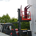Person arbeitet an einer Fassade und steht auf einer Gabelstaplerarbeitsbühne.