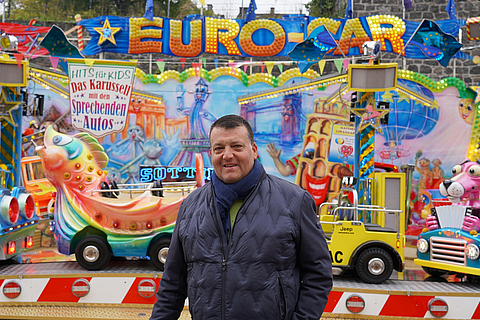 Marco Sottile vor seinem Kinderkarussell Euro-Car | © BGN | Ellen Weidenfeld Marco Sottile vor seinem Kinderkarussell Euro-Car