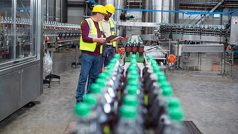 Zwei Mitarbeiter der Getränkeherstellung überwachen die Anlage