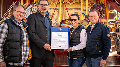 Stefan Weber und Rolf Jungebloed von der BGN überreichen  das Zertifikat „Sicher mit System“ an Anna Langenberg-Bienert und Toni Bienert (v. l. n. r.)