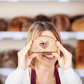Verkäuferin schaut durch ein Brot mit Herz