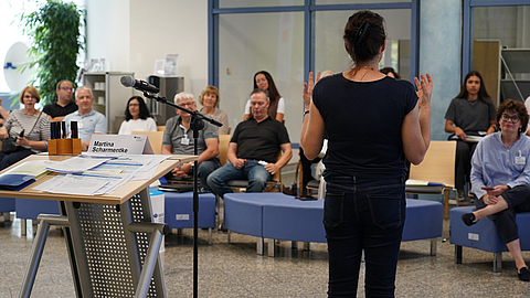 Gesundheitsmanager sichten Infomaterialien und unterhalten sich darüber an einem Tisch.